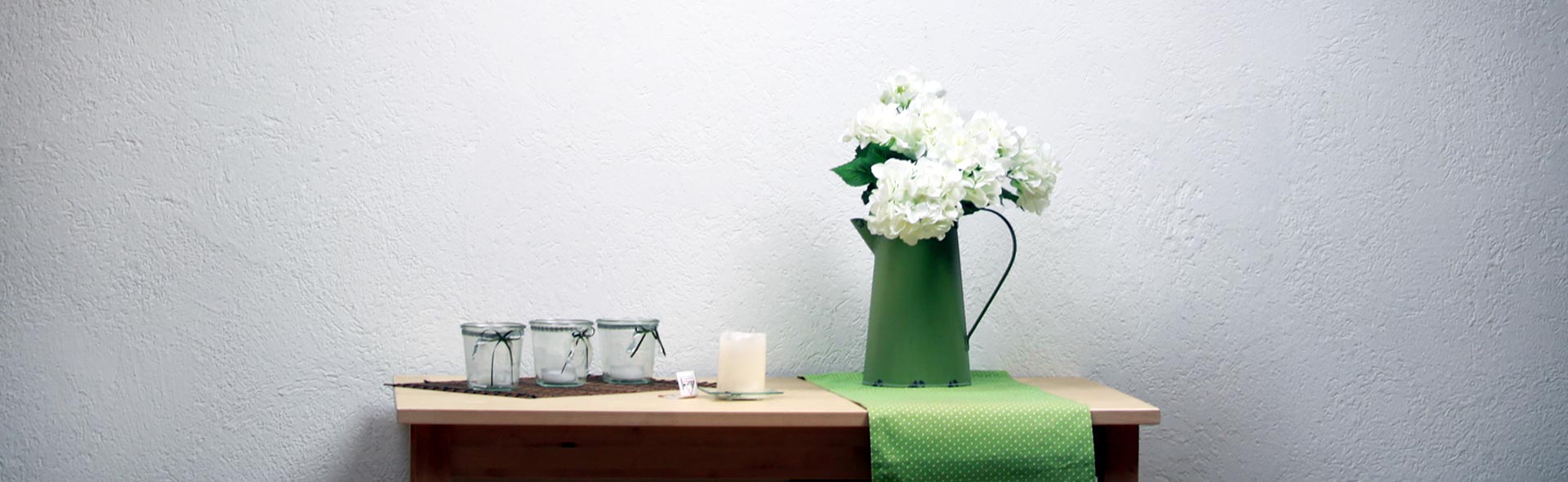 OJC Kommunität – Stilleben. Naturtisch mit Gläsern, Kanne, Kerze und weißen Blumen.